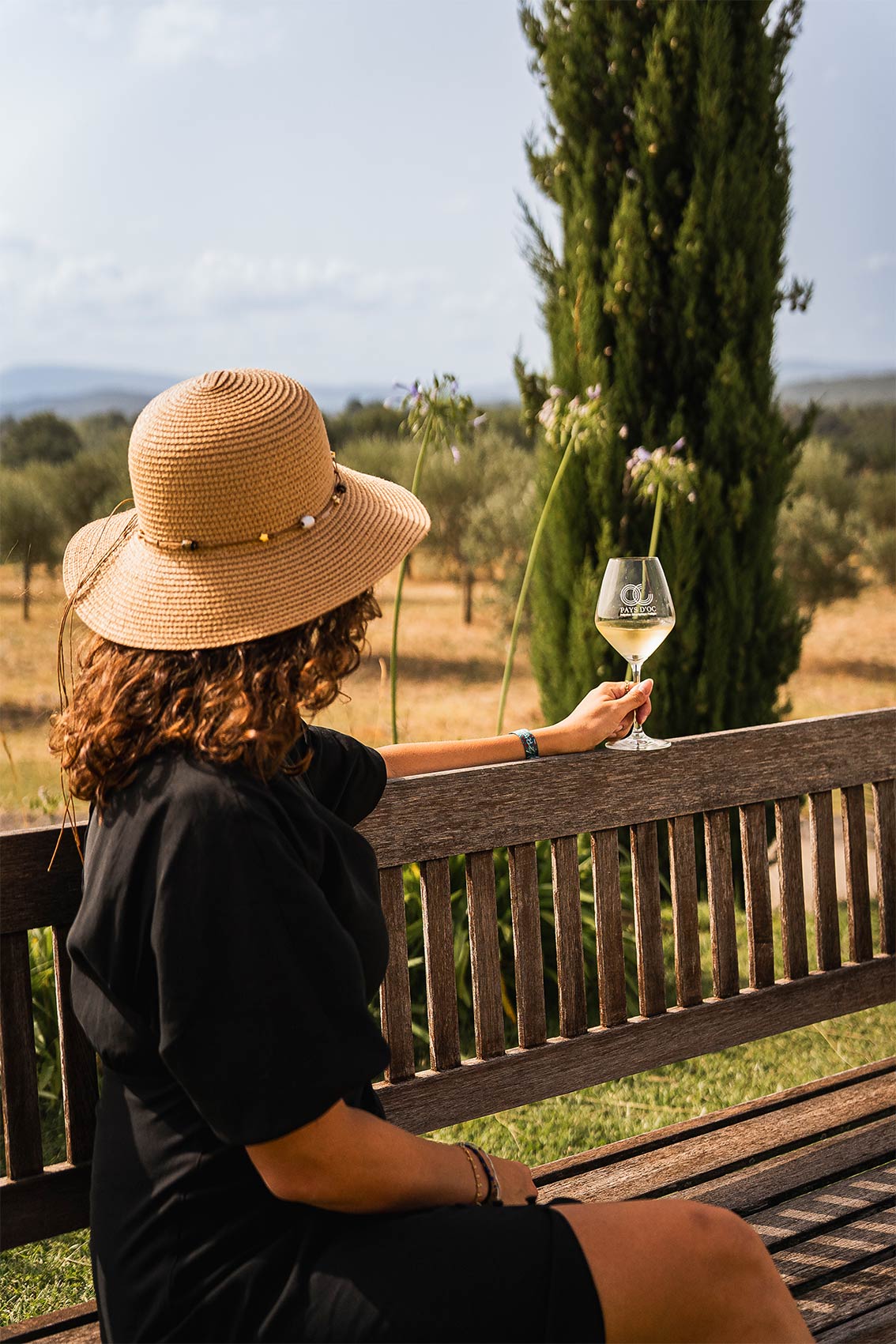 Photo shootée par le photographe professionnel Les insensés représentant un femme de dos tenant un verre de vin Pays d'Oc IGP