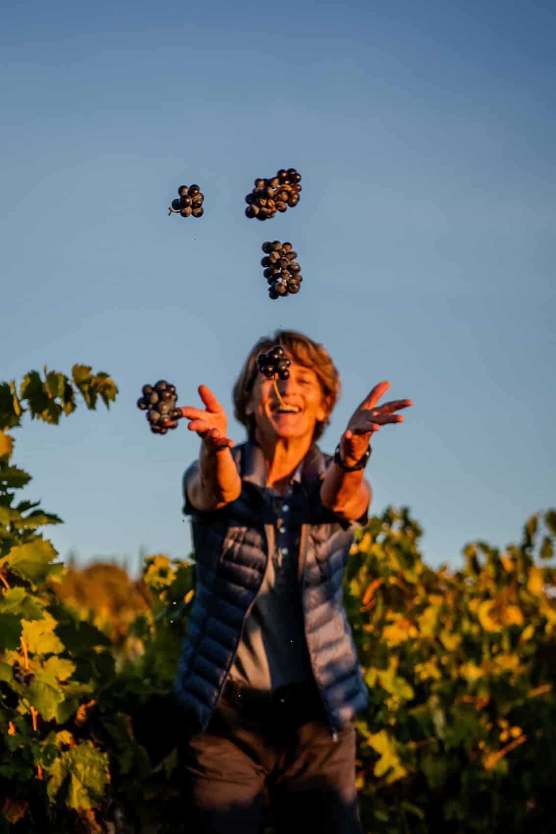 Photo amusante prise par le photographe professionnel Les insensés représentant une vigneronne Pays d'Oc IGP jouant avec des grappes de raisin